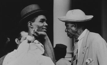 Movie still from “Salut les Cubains” (1963), directed by Agnès Varda – A man and an older man talking to each other; Close Up shot, Over the shoulder angle