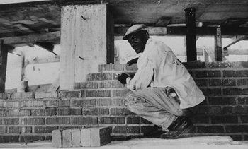 Movie still from “Salut les Cubains” (1963), directed by Agnès Varda – A man kneeling down next to a stack of bricks; Medium shot, Low angle
