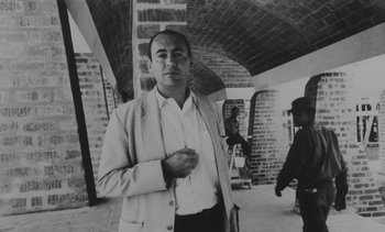 Movie still from “Salut les Cubains” (1963), directed by Agnès Varda – A man in a suit and tie standing under a brick wall; Medium shot, Low angle