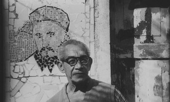 Movie still from “Salut les Cubains” (1963), directed by Agnès Varda – An older man wearing glasses standing in front of a brick wall; Close Up shot, Low angle