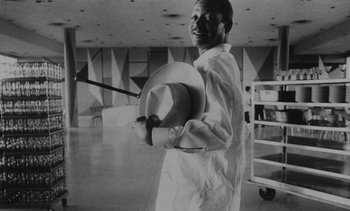 Movie still from “Salut les Cubains” (1963), directed by Agnès Varda – A black and white photo of a man holding a hat; Medium shot, Low angle