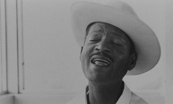 Movie still from “Salut les Cubains” (1963), directed by Agnès Varda – A black and white photo of a man wearing a cowboy hat; Extreme Close Up shot, High angle