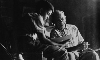 Movie still from “Salut les Cubains” (1963), directed by Agnès Varda – An older man sitting next to a young boy; Medium shot, Over the shoulder angle