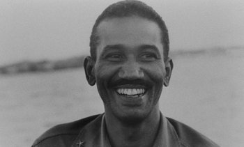 Movie still from “Salut les Cubains” (1963), directed by Agnès Varda – An old black and white photo of a man smiling for the camera; Close Up shot, Low angle