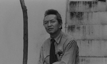 Movie still from “Salut les Cubains” (1963), directed by Agnès Varda – An old black and white photo of a man in a tie; Close Up shot, Low angle