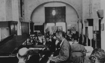 Movie still from “Salut les Cubains” (1963), directed by Agnès Varda – An old black and white photo of a man playing the piano; Extreme Wide shot, High angle