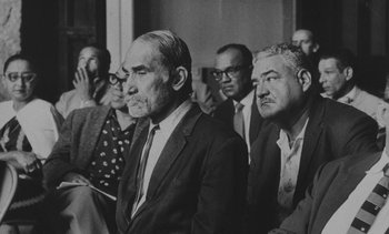 Movie still from “Salut les Cubains” (1963), directed by Agnès Varda – Black and white photograph of men in suits and ties; Medium shot, Over the shoulder angle