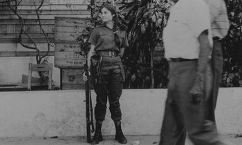 Movie still from “Salut les Cubains” (1963), directed by Agnès Varda – An old photo of a woman holding a rifle; Medium shot, Low angle