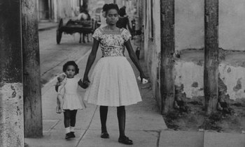 Movie still from “Salut les Cubains” (1963), directed by Agnès Varda – A woman and a little girl walking down a sidewalk; Wide shot, Low angle