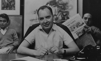 Movie still from “Salut les Cubains” (1963), directed by Agnès Varda – Black and white photograph of a man sitting at a desk; Medium shot, Low angle