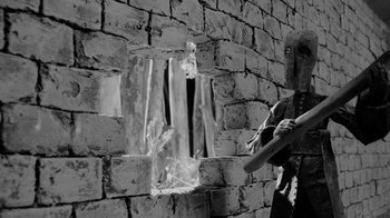 Movie still from “Salvation Has No Name” (2022), directed by Joseph Wallace – A person standing in front of a brick wall; Medium shot, Low angle