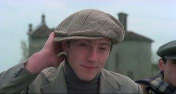 Movie still from “Salò, or the 120 Days of Sodom” (1975), directed by Pier Paolo Pasolini – A young man wearing a hat and a jacket; Close Up shot, Low angle