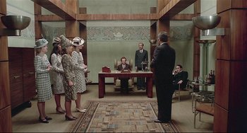 Movie still from “Salò, or the 120 Days of Sodom” (1975), directed by Pier Paolo Pasolini – A group of people standing around a table; Wide shot, Overhead angle