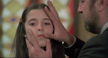 Movie still from “Salò, or the 120 Days of Sodom” (1975), directed by Pier Paolo Pasolini – A man touching a young girl's face with her hands; Close Up shot, Over the shoulder angle