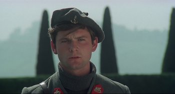 Movie still from “Salò, or the 120 Days of Sodom” (1975), directed by Pier Paolo Pasolini – A young man in a military uniform is looking at the camera; Close Up shot, Low angle