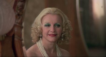 Movie still from “Salò, or the 120 Days of Sodom” (1975), directed by Pier Paolo Pasolini – A woman with blonde hair and green eye shadow; Close Up shot, Over the shoulder angle