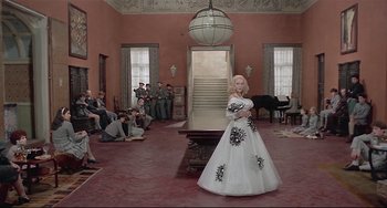 Movie still from “Salò, or the 120 Days of Sodom” (1975), directed by Pier Paolo Pasolini – A woman in a white dress in front of a group of people; Wide shot, High angle