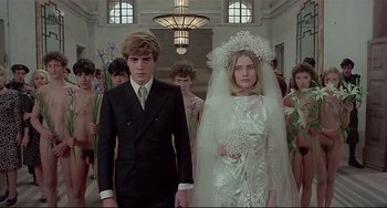Movie still from “Salò, or the 120 Days of Sodom” (1975), directed by Pier Paolo Pasolini – A man and a woman in wedding attire in front of a group of people; Medium shot, Low angle