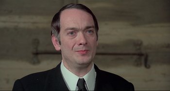 Movie still from “Salò, or the 120 Days of Sodom” (1975), directed by Pier Paolo Pasolini – A person wearing a suit and tie; Close Up shot, Over the shoulder angle