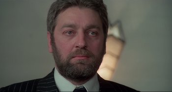 Movie still from “Salò, or the 120 Days of Sodom” (1975), directed by Pier Paolo Pasolini – A person wearing a suit and tie; Close Up shot, Low angle