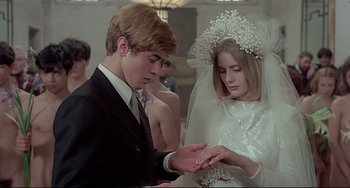 Movie still from “Salò, or the 120 Days of Sodom” (1975), directed by Pier Paolo Pasolini – A man and a woman in wedding attire holding hands; Medium shot, Low angle