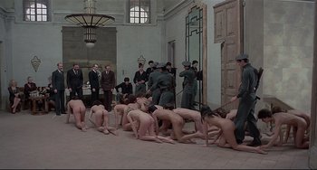 Movie still from “Salò, or the 120 Days of Sodom” (1975), directed by Pier Paolo Pasolini – A group of naked people kneeling in front of men; Wide shot, High angle