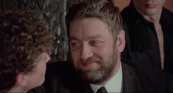 Movie still from “Salò, or the 120 Days of Sodom” (1975), directed by Pier Paolo Pasolini – A person wearing a suit and tie; Close Up shot, Over the shoulder angle