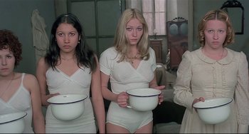 Movie still from “Salò, or the 120 Days of Sodom” (1975), directed by Pier Paolo Pasolini – A group of women in white underwear holding bowls; Medium shot, High angle