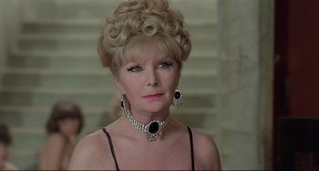 Movie still from “Salò, or the 120 Days of Sodom” (1975), directed by Pier Paolo Pasolini – An older woman wearing a necklace and earrings; Close Up shot, Over the shoulder angle