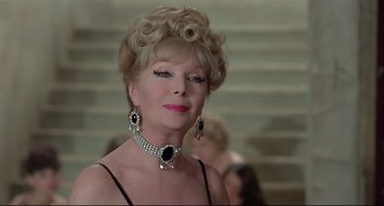 Movie still from “Salò, or the 120 Days of Sodom” (1975), directed by Pier Paolo Pasolini – An older woman wearing a necklace and earrings; Close Up shot, Over the shoulder angle