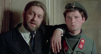 Movie still from “Salò, or the 120 Days of Sodom” (1975), directed by Pier Paolo Pasolini – A man and a man in a suit posing for a picture; Close Up shot, Low angle