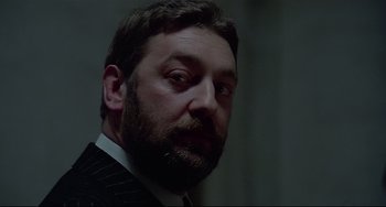 Movie still from “Salò, or the 120 Days of Sodom” (1975), directed by Pier Paolo Pasolini – A person wearing a suit and tie; Close Up shot, Low angle