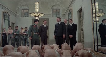 Movie still from “Salò, or the 120 Days of Sodom” (1975), directed by Pier Paolo Pasolini – A group of men standing next to each other in a room; Wide shot, Low angle