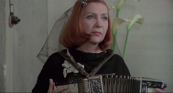 Movie still from “Salò, or the 120 Days of Sodom” (1975), directed by Pier Paolo Pasolini – A woman holding an accordion in front of a mirror; Close Up shot, Low angle
