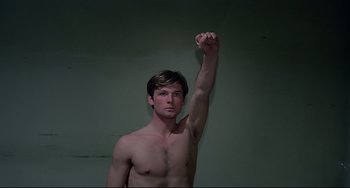 Movie still from “Salò, or the 120 Days of Sodom” (1975), directed by Pier Paolo Pasolini – A shirtless man raises his arm in the air; Medium shot, Overhead angle