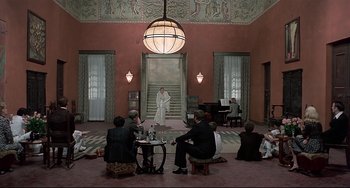 Movie still from “Salò, or the 120 Days of Sodom” (1975), directed by Pier Paolo Pasolini – A group of people sitting in a room with a man in a white robe; Wide shot, High angle