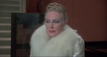 Movie still from “Salò, or the 120 Days of Sodom” (1975), directed by Pier Paolo Pasolini – An older woman wearing a white dress and a white fur coat; Close Up shot, Over the shoulder angle