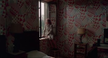 Movie still from “Salò, or the 120 Days of Sodom” (1975), directed by Pier Paolo Pasolini – A woman sitting on a window ledge looking out a window; Wide shot, High angle