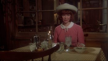 Movie still from “Same Time, Next Year” (1978), directed by Robert Mulligan – A woman sitting at a table with a plate of food in front of her; Medium shot, Over the shoulder angle