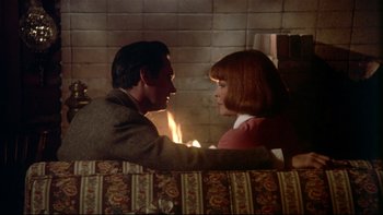 Movie still from “Same Time, Next Year” (1978), directed by Robert Mulligan – A man and a woman sitting in front of a fireplace; Medium shot, High angle