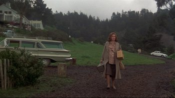 Movie still from “Same Time, Next Year” (1978), directed by Robert Mulligan – A woman walking down a dirt road holding shopping bags; Wide shot, Low angle