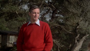 Movie still from “Same Time, Next Year” (1978), directed by Robert Mulligan – A man in a red sweater standing next to a tree; Medium shot, Low angle