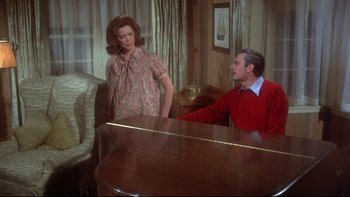 Movie still from “Same Time, Next Year” (1978), directed by Robert Mulligan – A man and a woman standing next to a piano in a room; Medium shot, High angle