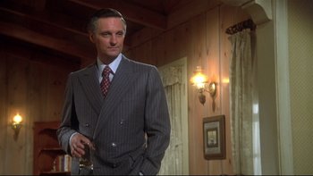 Movie still from “Same Time, Next Year” (1978), directed by Robert Mulligan – A man in a suit and tie standing in front of a wall; Medium shot, Low angle