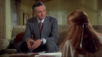 Movie still from “Same Time, Next Year” (1978), directed by Robert Mulligan – A man sitting in front of a woman in front of a mirror; Medium shot, Over the shoulder angle