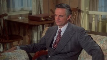 Movie still from “Same Time, Next Year” (1978), directed by Robert Mulligan – A man in a suit and tie sitting in a chair; Medium shot, High angle