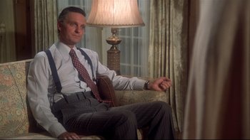 Movie still from “Same Time, Next Year” (1978), directed by Robert Mulligan – A man sitting on a chair in a room; Medium shot, Low angle