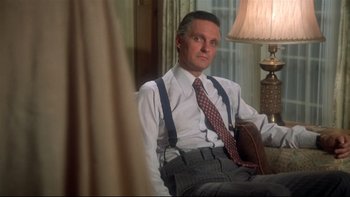 Movie still from “Same Time, Next Year” (1978), directed by Robert Mulligan – A man sitting in a chair wearing suspenders and a tie; Medium shot, Low angle
