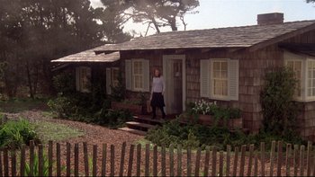 Movie still from “Same Time, Next Year” (1978), directed by Robert Mulligan – A woman standing on the steps of a wooden house; Wide shot, Low angle