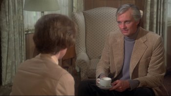 Movie still from “Same Time, Next Year” (1978), directed by Robert Mulligan – An older man sitting in a chair holding a coffee cup; Medium shot, Over the shoulder angle